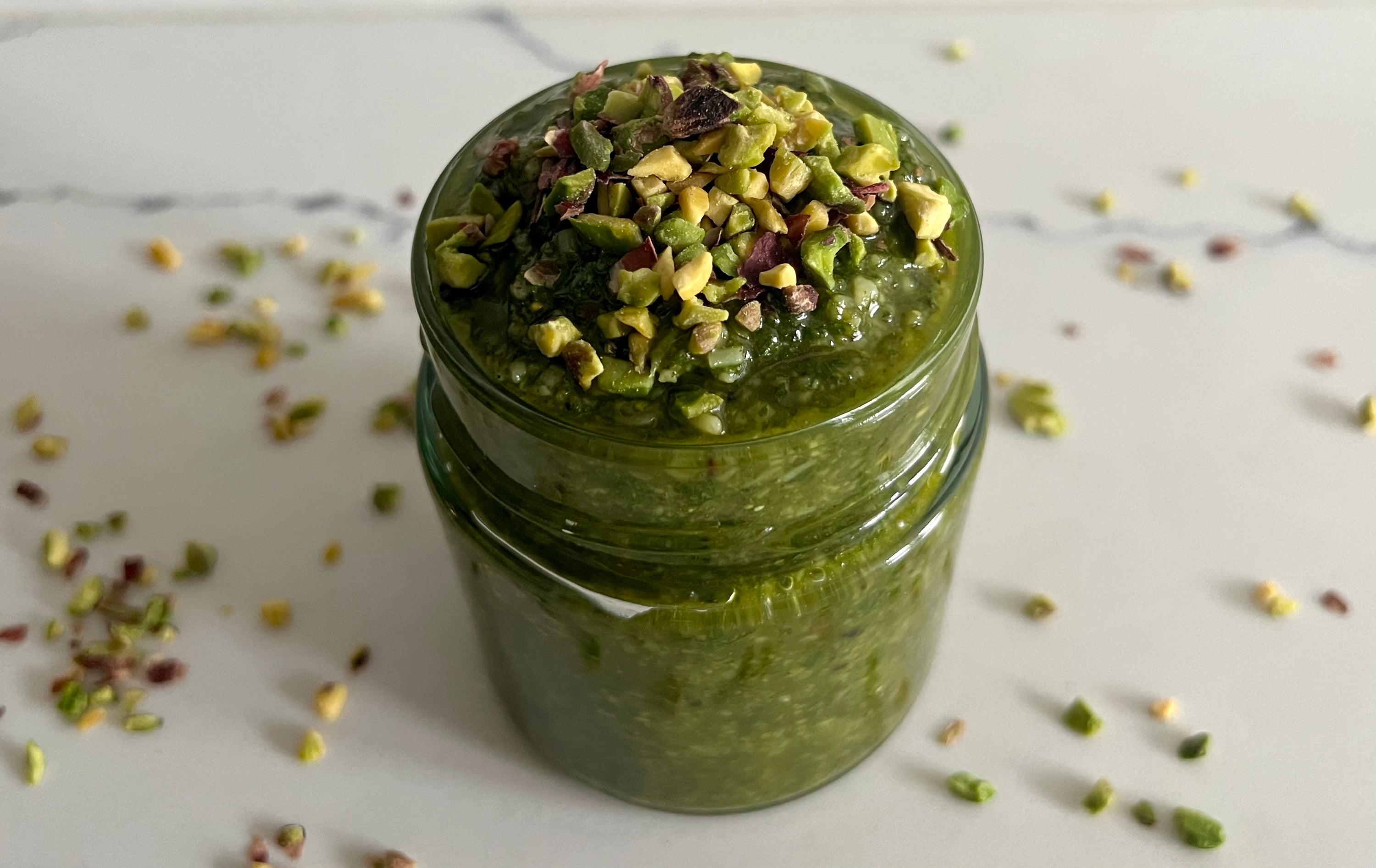 vibrant pistachio pesto made with pistachio butter and fresh basil, showcasing a creamy, green sauce perfect for pasta, sandwiches, or as a dip. pine nut free pesto. peppertux pistachio pesto