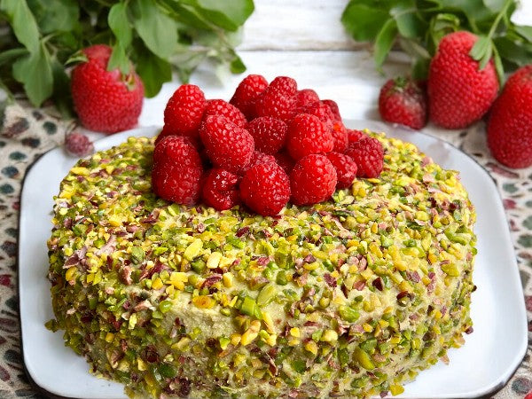 pistachio chocolate raspberry cake, featuring layers of rich chocolate cake, creamy pistachio filling, and fresh raspberries, topped with a garnish of chopped pistachios and raspberries